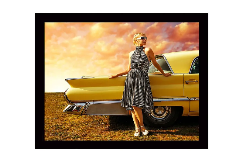Innrammet trelerretsbilde - 41x56 cm - Kvinne i prikkete kjole lener seg mot en veteranbil, Gul / Svart / Hvit