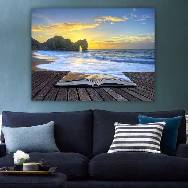 Lerretsbilde 70x100 cm - Åpen bok liggende på en trebrygge med en solnedgang ved havet i bakgrunnen - Blå / Oransje / Beige - Interiør - Maleri & posters - Lerretsbilder