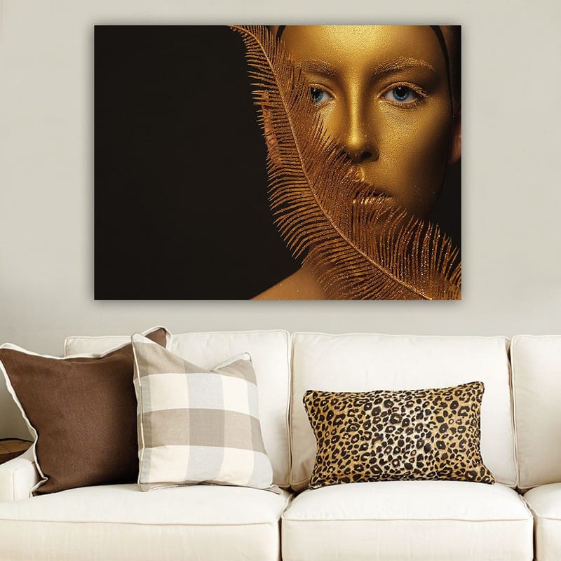 Lerretsbilde 70x100 cm - Ansiktsportrett med gyllen overflate og blå øyne, omgitt av en dekorativ fjærlignende struktur, Gull / Blå