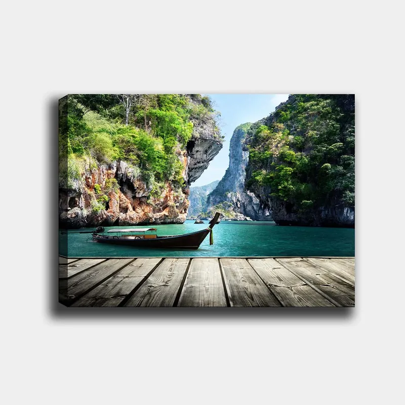 Lerretsbilde 70x100 cm - Båten ligger stille på en steinete strand omgitt av frodige fjell og klart vann, Grønn / Blå / Brun