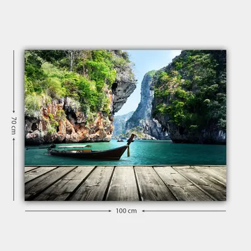 Lerretsbilde 70x100 cm - Båten ligger stille på en steinete strand omgitt av frodige fjell og klart vann - Grønn / Blå / Brun - Interiør - Maleri & posters - Lerretsbilder