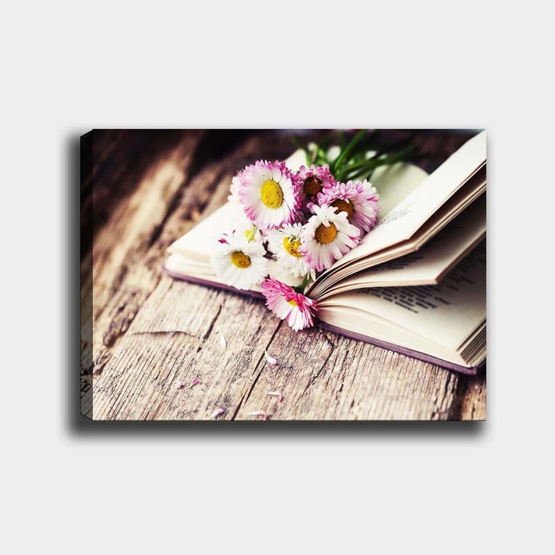 Lerretsbilde 70x100 cm - Blomsterbukett plassert på en åpen bok, Hvit / Rosa / Gul