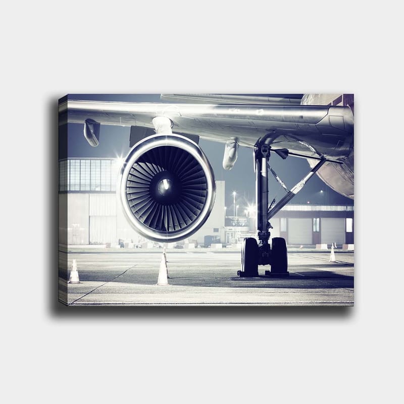 Lerretsbilde 70x100 cm - Detaljert visning av en flymotor og understellet på en flyplass, Grå / Svart / Sølv