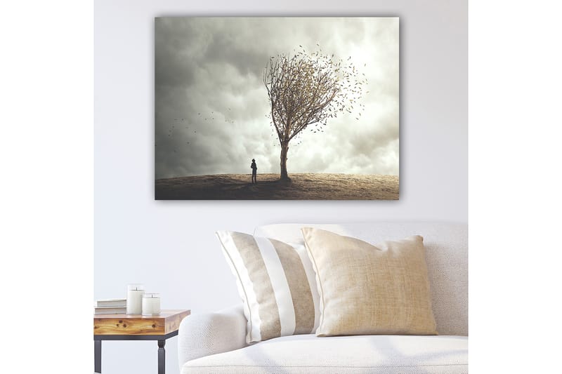 Lerretsbilde 70x100 cm - En enslig person står ved et tre som mister bladene sine i en dramatisk og overskyet himmel, Grå / Brun / Beige