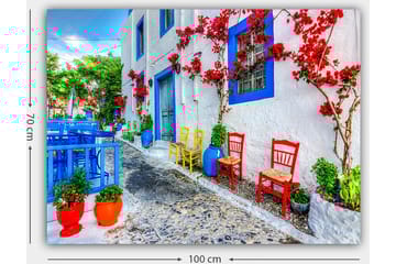 Lerretsbilde 70x100 cm - Fargerik gate med blomster og stoler i forskjellige farger som skaper en livlig atmosfære - Blå / Rød / Grønn - Interiør - Maleri & posters - Lerretsbilder