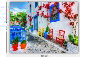 Lerretsbilde 70x100 cm - Fargerik gate med blomster og stoler i forskjellige farger som skaper en livlig atmosfære - Blå / Rød / Grønn - Interiør - Maleri & posters - Lerretsbilder