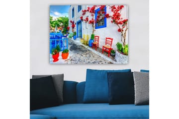 Lerretsbilde 70x100 cm - Fargerik gate med blomster og stoler i forskjellige farger som skaper en livlig atmosfære - Blå / Rød / Grønn - Interiør - Maleri & posters - Lerretsbilder