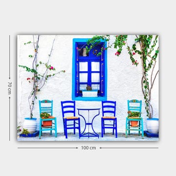 Lerretsbilde 70x100 cm - Fargerik utendørs spiseplass med blå stoler og vinduer i middelhavsmiljø - Blå / Grønn / Hvit - Interiør - Maleri & posters - Lerretsbilder