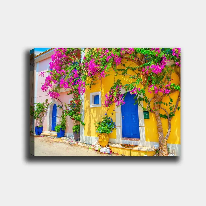 Lerretsbilde 70x100 cm - Fargerike hus med bougainvillea som blomstrer i en travel gate, Blå / Gul / Rosa