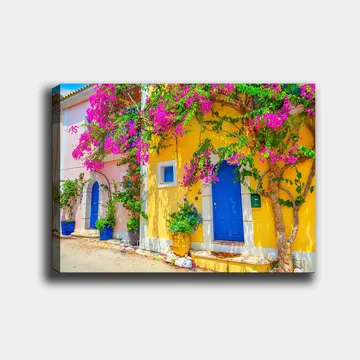 Lerretsbilde 70x100 cm - Fargerike hus med bougainvillea som blomstrer i en travel gate - Blå / Gul / Rosa - Interiør - Maleri & posters - Lerretsbilder