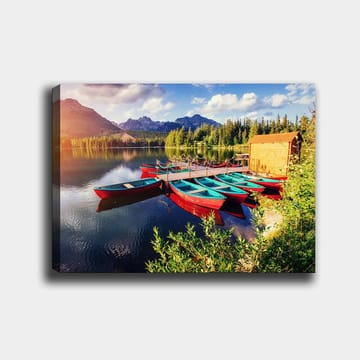 Lerretsbilde 70x100 cm - Flere fargerike båter ligger på en speilblank innsjø omgitt av frodige trær og fjell - Rød / Turkis / Grønn - Interiør - Maleri & posters - Lerretsbilder