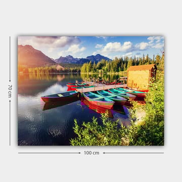 Lerretsbilde 70x100 cm - Flere fargerike båter ligger på en speilblank innsjø omgitt av frodige trær og fjell - Rød / Turkis / Grønn - Interiør - Maleri & posters - Lerretsbilder