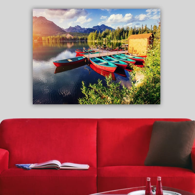Lerretsbilde 70x100 cm - Flere fargerike båter ligger på en speilblank innsjø omgitt av frodige trær og fjell - Rød / Turkis / Grønn - Interiør - Maleri & posters - Lerretsbilder