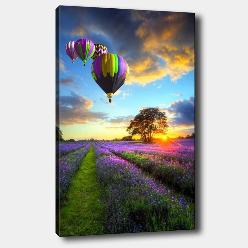 Lerretsbilde 70x100 cm - Flere fargerike varmluftsballonger svever over et lavendelfelt i solnedgangens lys, Lilla / Grønn / Svart