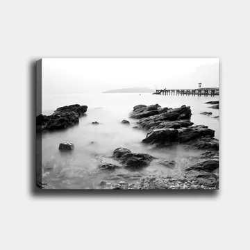 Lerretsbilde 70x100 cm - Fredelig kystlandskap med klipper og en brygge i det fjerne - Svart / Hvit / Grå - Interiør - Maleri & posters - Lerretsbilder