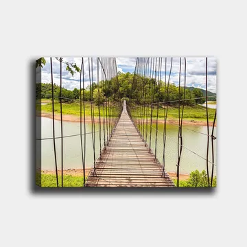 Lerretsbilde 70x100 cm - Hengebro som går over en rolig innsjø, omgitt av frodig grøntområde - Grønn / Brun / Blå - Interiør - Maleri & posters - Lerretsbilder