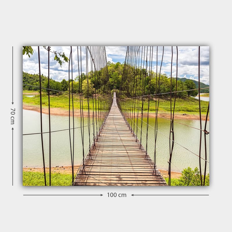 Lerretsbilde 70x100 cm - Hengebro som går over en rolig innsjø, omgitt av frodig grøntområde - Grønn / Brun / Blå - Interiør - Maleri & posters - Lerretsbilder