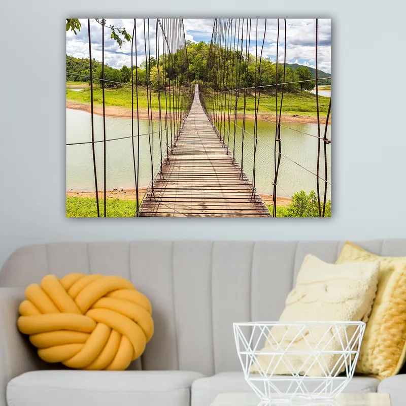 Lerretsbilde 70x100 cm - Hengebro som går over en rolig innsjø, omgitt av frodig grøntområde - Grønn / Brun / Blå - Interiør - Maleri & posters - Lerretsbilder