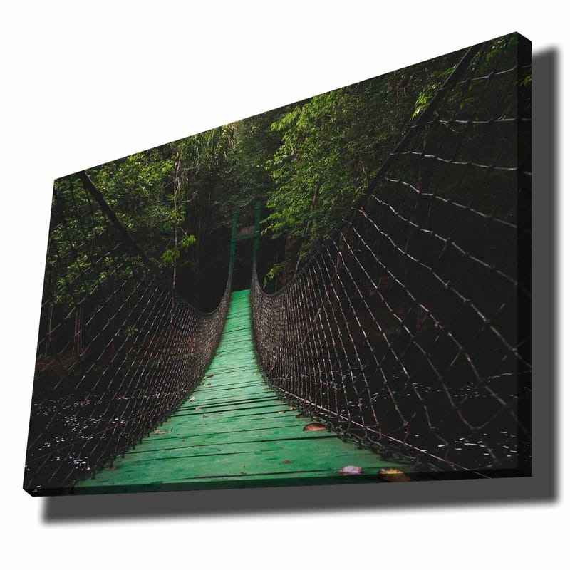 Lerretsbilde 70x100 cm - Hengebro som strekker seg gjennom en frodig skog, Grønn / Svart