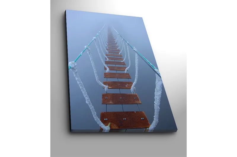 Lerretsbilde 70x100 cm - Hengebro som strekker seg gjennom tåken og skaper en mystisk og fjern følelse - Mørk brun / Hvit / Lys blå - Interiør - Maleri & posters - Lerretsbilder