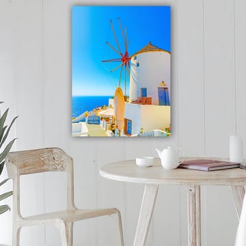 Lerretsbilde 70x100 cm - Hvit vindmølle med rød rotor på en klippe ved havet, omgitt av klar blå himmel og hav - Hvit / Rød / Blå - Interiør - Maleri & posters - Lerretsbilder
