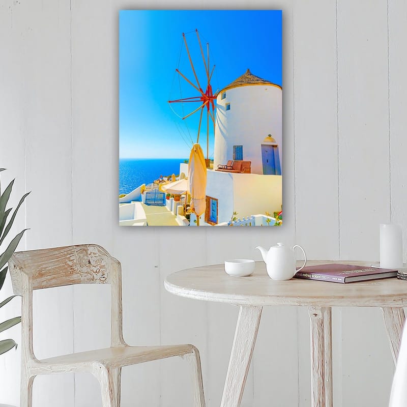 Lerretsbilde 70x100 cm - Hvit vindmølle med rød rotor på en klippe ved havet, omgitt av klar blå himmel og hav - Hvit / Rød / Blå - Interiør - Maleri & posters - Lerretsbilder