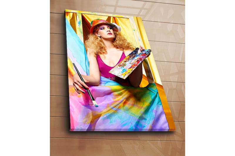 Lerretsbilde 70x100 cm - Kreativ kvinne som maler med en palett i hånden, omgitt av fargerike stoffer - Rosa / Blå / Gul - Interiør - Maleri & posters - Lerretsbilder