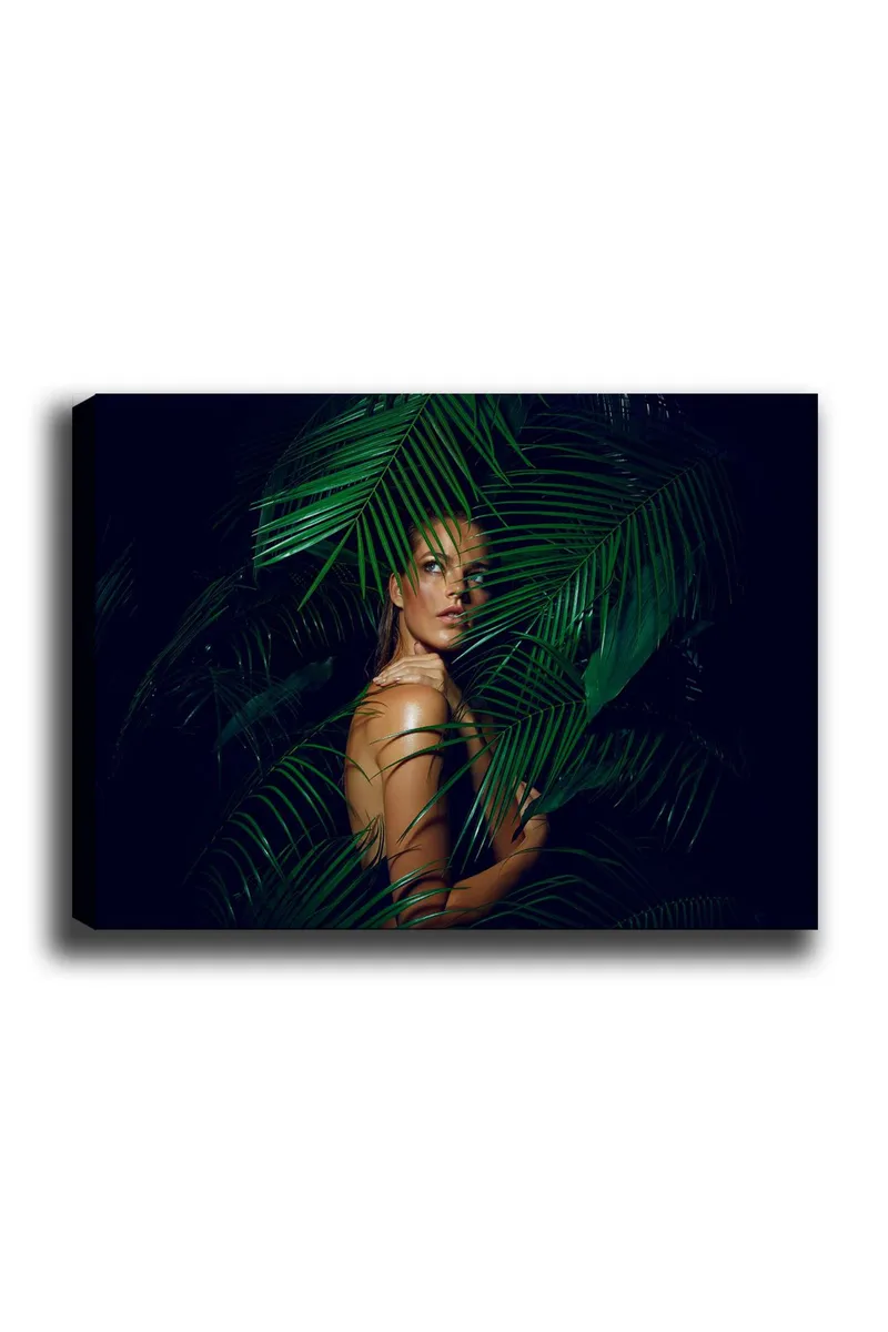 Lerretsbilde 70x100 cm - Kvinne delvis skjult bak grønne palmeblader, Mørk grønn / Lys grønn / Beige