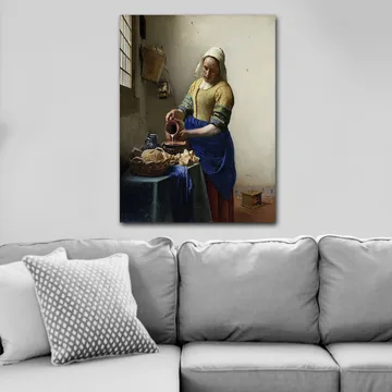 Lerretsbilde 70x100 cm - Kvinne som heller melk i en bolle på et lyst kjøkken - Blå / Gul / Brun - Interiør - Maleri & posters - Lerretsbilder