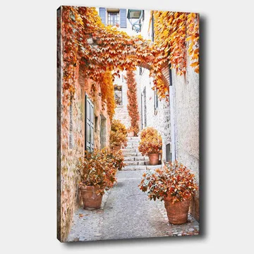 Lerretsbilde 70x100 cm - Malerisk smug omgitt av fargerike høstblader og potteplanter - Oransje / Brun / Gul - Interiør - Maleri & posters - Lerretsbilder