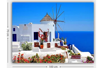 Lerretsbilde 70x100 cm - Malerisk utsikt over en hvitkalket bygning med en tradisjonell vindmølle og fargerike blomster på Santorini - Hvit / Blå / Rød - Interiør - Maleri & posters - Lerretsbilder