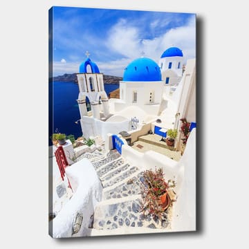 Lerretsbilde 70x100 cm - Malerisk utsikt over hvite hus med blå kupler og en asfaltert vei i en gresk øy-setting - Blå / Hvit - Interiør - Maleri & posters - Lerretsbilder