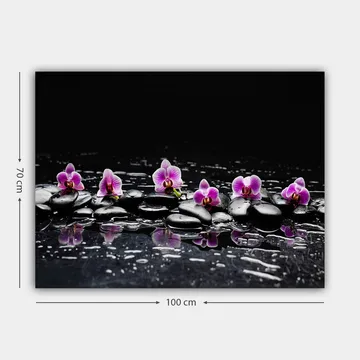 Lerretsbilde 70x100 cm - Rad med lilla orkideer som hviler på svarte steiner med refleksjoner i vann - Lilla / Svart - Interiør - Maleri & posters - Lerretsbilder
