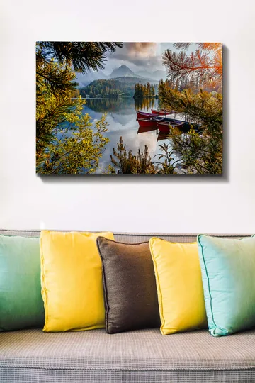 Lerretsbilde 70x100 cm - Rolig innsjø med en rød båt ved en trebrygge, omgitt av frodige trær og fjerne fjell - Grønn / Rød / Blå - Interiør - Maleri & posters - Lerretsbilder