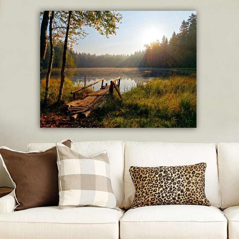 Lerretsbilde 70x100 cm - Rolig innsjø med en trebro omgitt av frodige trær og morgensolens stråler - Grønn / Brun / Gul - Interiør - Maleri & posters - Lerretsbilder