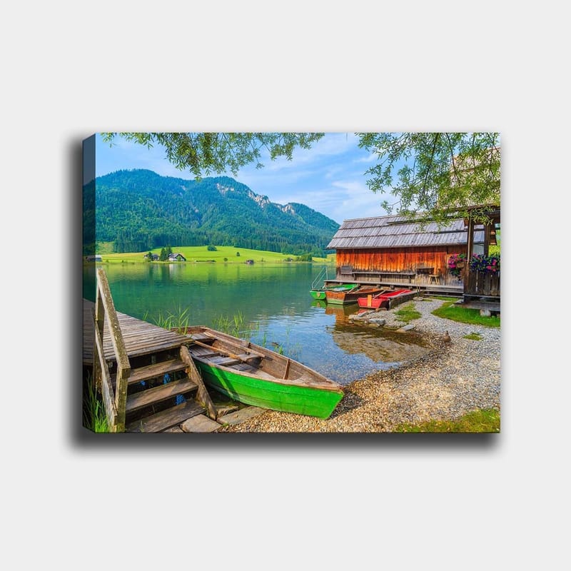 Lerretsbilde 70x100 cm - Rolig innsjø med fargerike båter ved en trebrygge og omkringliggende grønne fjell, Grønn / Blå / Brun