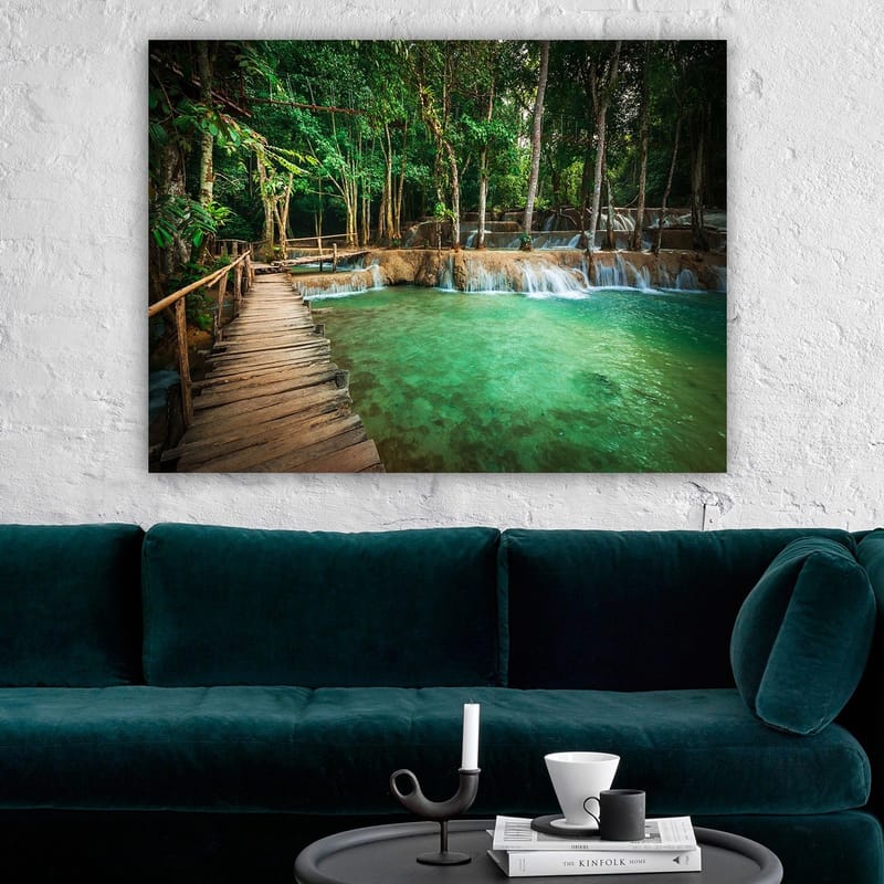 Lerretsbilde 70x100 cm - Rolig og naturskjønt sted med en trebro som fører over et klart, turkis fossefallbasseng omgitt av frodig grøntområde - Turkis / Grønn / Brun - Interiør - Maleri & posters - Lerretsbilder