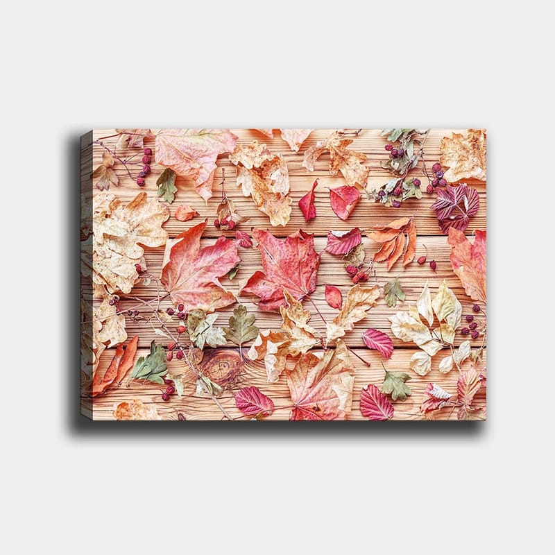Lerretsbilde 70x100 cm - Samling av høstblader i forskjellige farger som ligger på en treflate - Rød / Gul / Grønn - Interiør - Maleri & posters - Lerretsbilder
