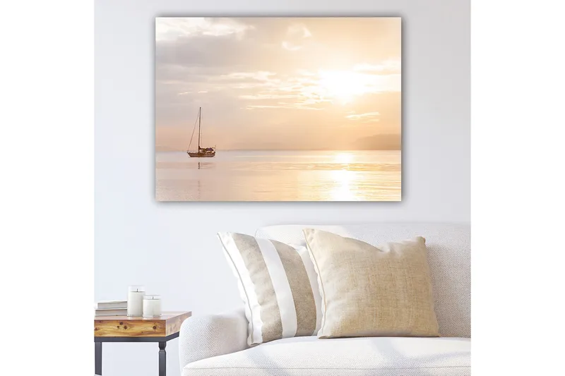 Lerretsbilde 70x100 cm - Seilbåt glir over en speilblank innsjø i et mykt, gyllent lys, Gull / Lys brun / Beige