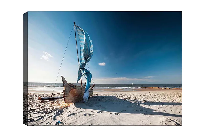 Lerretsbilde 70x100 cm - Seilbåt med blå seil på en strand, Blå / Beige / Brun