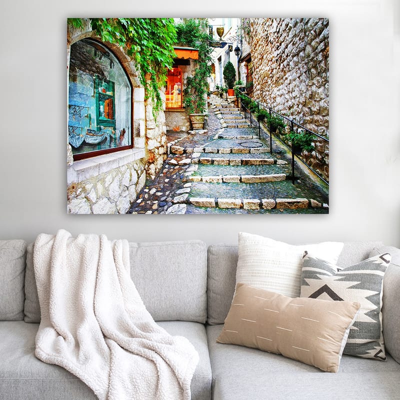 Lerretsbilde 70x100 cm - Sjarmerende smug med steiner og grøntområder som fører oppover, omgitt av historiske bygninger - Grønn / Beige / Oransje - Interiør - Maleri & posters - Lerretsbilder