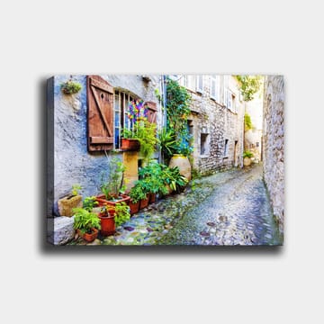 Lerretsbilde 70x100 cm - Sjarmerende smug med steinhus og blomsterpotter som skaper en livlig atmosfære - Grønn / Blå / Beige - Interiør - Maleri & posters - Lerretsbilder