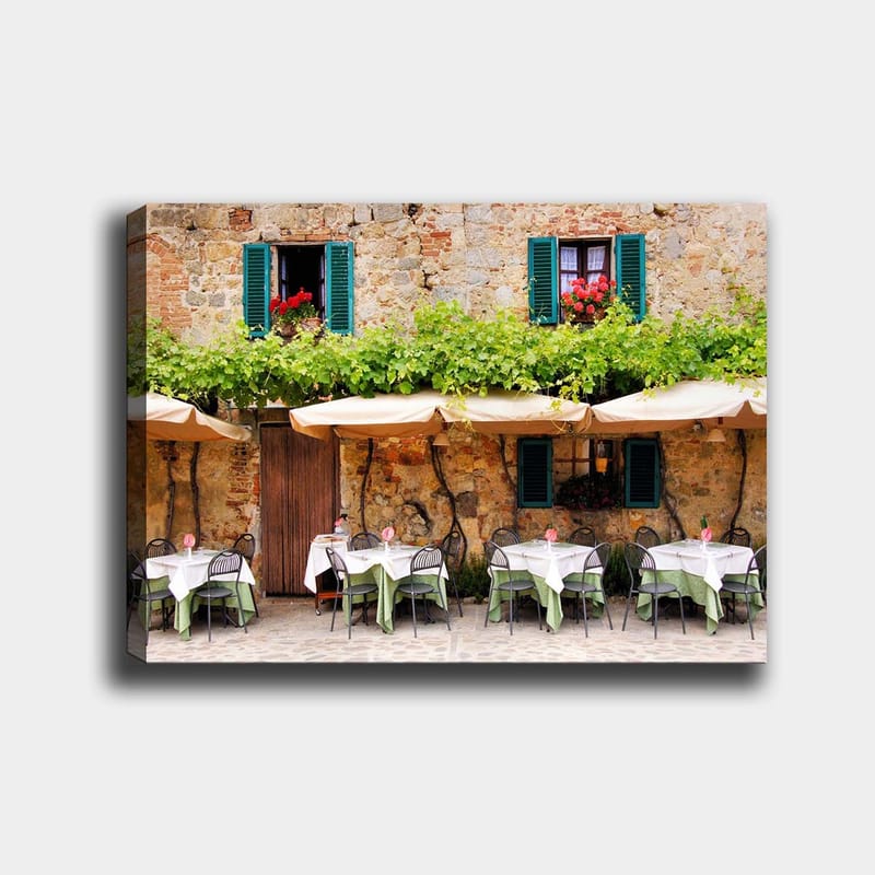 Lerretsbilde 70x100 cm - Sjarmerende utendørs spiseplass med hvite bord og grønne duker foran en gammel steinbygning med mørkegrønne skodder, Mørkegrønn / Hvit / Mursteinsrød
