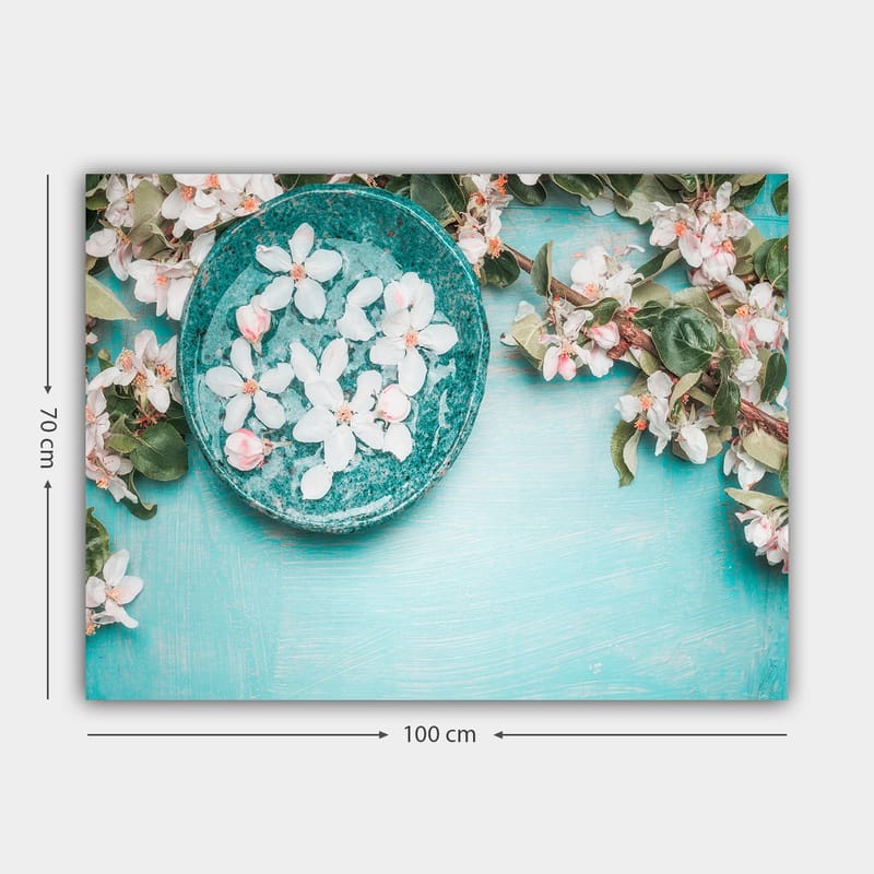 Lerretsbilde 70x100 cm - Skål med blomster omgitt av frodige grønne kvister og blomster på en lyseblå bakgrunn - Turkis / Hvit / Rosa - Interiør - Maleri & posters - Lerretsbilder
