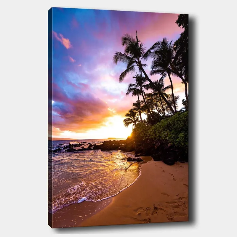 Lerretsbilde 70x100 cm - Solnedgang på stranden med palmer innrammet av fargerike skyer, Lilla / Oransje / Grønn