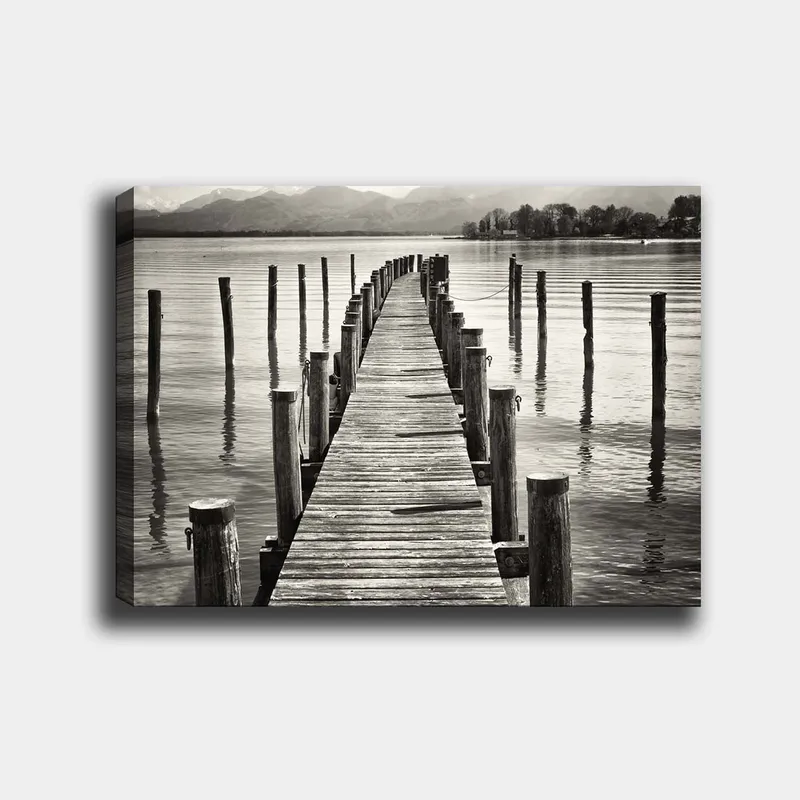 Lerretsbilde 70x100 cm - Stille brygge som strekker seg ut over vannet, omgitt av søyler som speiler seg i overflaten, Svart / Hvit / Grå