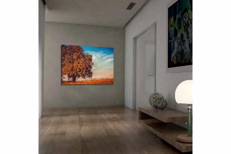 Lerretsbilde 70x100 cm - Stor, oransje trekrone i høstfarger mot en klar blå himmel, Oransje / Blå / Beige