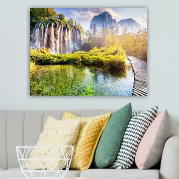 Lerretsbilde 70x100 cm - Storslått fossefall omgitt av frodig vegetasjon og majestetiske fjell - Grønn / Blå / Gul - Interiør - Maleri & posters - Lerretsbilder