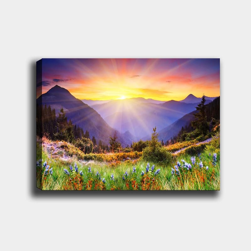 Lerretsbilde 70x100 cm - Storslått soloppgang over fjell og frodige enger, Gull / Lilla / Grønn