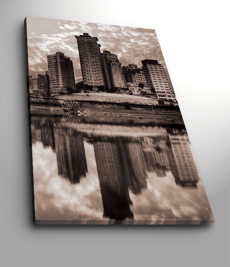 Lerretsbilde 70x100 cm - Svart-hvitt bysilhuett med høye bygninger speilet i vannet, Svart / Hvit / Grå